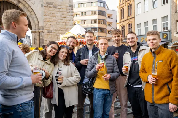 Eine Gruppe lächelnder Gäste mit Getränken vor der Severinstorburg