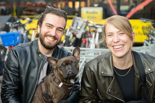 Ein lachendes Paar in Lederjacken mit seinem Hund