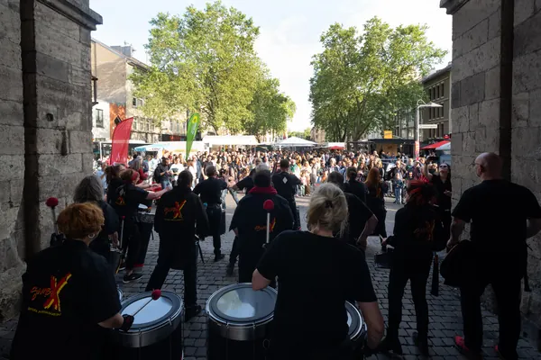 Trommelgruppe in schwarzen Shirts spielt vor dem Publikum auf dem Chlodwigplatz