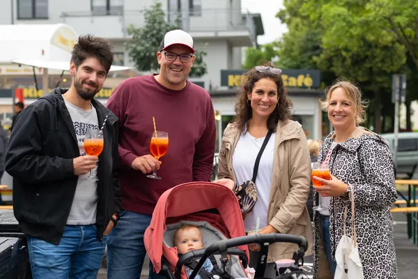Vier Erwachsene mit Spritz-Gläsern, davor ein Baby im Kinderwagen