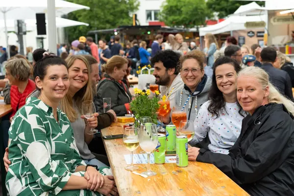 Gut gelaunte Gruppe an einem Holztisch mit Blumen und Getränken