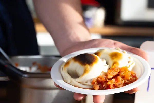 Ein Teller mit zwei Empanadas und Tomatensoße