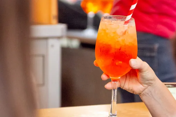 Ein Glas Aperol Spritz mit rot-weißem Strohhalm