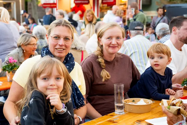 Zwei Frauen und zwei Kinder lächeln an einer Bierbank