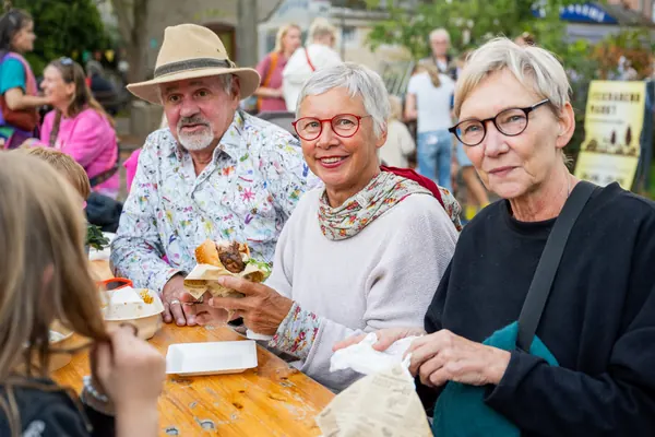 Drei ältere Gäste lächeln an einem Tisch mit Essen
