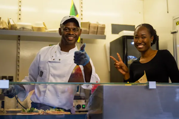 Lachendes Küchenteam hinter der Theke eines Streetfood-Stands