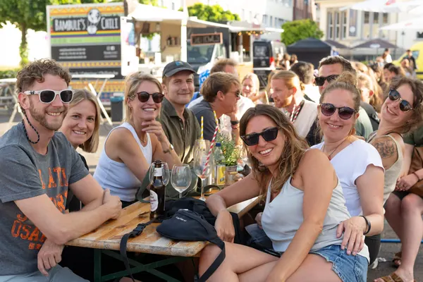Eine Gruppe mit Sonnenbrillen lacht an einem Biertisch