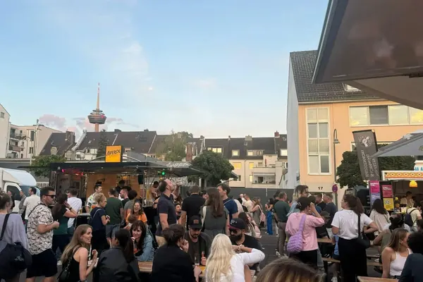 Viele Besucher auf dem Neptunplatz am frühen Abend, im Hintergrund ein Fernsehturm