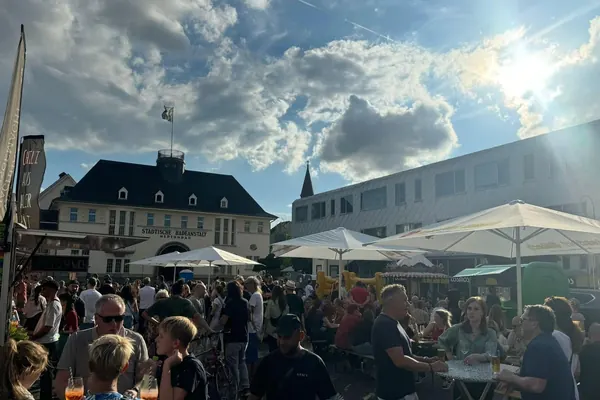 Sonne über dem Neptunplatz mit Gästen unter Schirmen vor dem Neptunbad