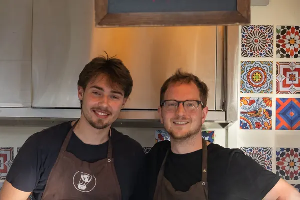 Zwei junge Männer mit Schürzen an einem Nachos-Stand